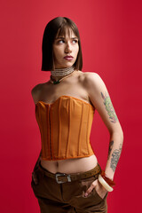 Young woman showcases modern style against a vibrant red backdrop with confidence and grace