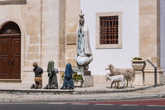 Statue of Our Lady of Fatima with the three shepherd children, L&uacute;cia, Francisco, and Jacinta, kneeling in prayer outside a church in Porto de Mos.