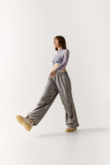 Young woman showcases stylish outfit in modern fashion pose on a bright background