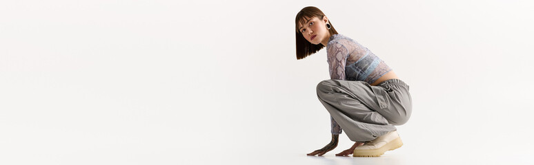 Stylish young woman showing off trendy fashion in a minimalist studio setting