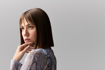 Young woman showcases modern fashion with effortless elegance against a neutral backdrop