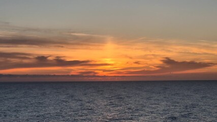 Sunset, ocean, water. Beautiful vertical shot of fiery orange twilight illuminating the vast open horizon.