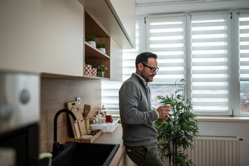 Man drinking coffee in modern kitchen at home