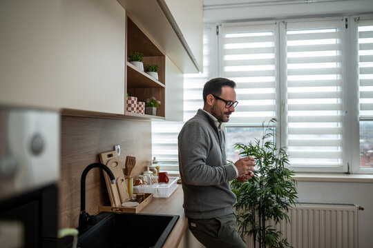 Man drinking coffee in modern kitchen at home - Powered by Adobe