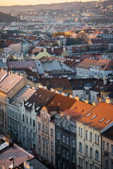 Obraz premium Warm evening light casting over the historic rooftops of Prague, captured from Nusle Bridge, revealing layers of charming architecture and autumn-tinted cityscape.