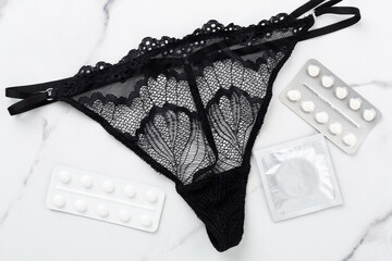 Contraceptive pills and condoms on marble background, top view. birth control methods