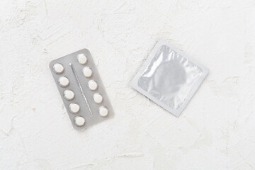 Contraceptive pills and condoms on concrete background, top view. birth control methods