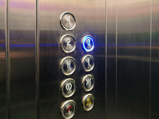 Elevator control panel showcases accessibility features with braille alongside floor numbers and directional symbols. The blue illuminated number three signifies the current or selected floor.