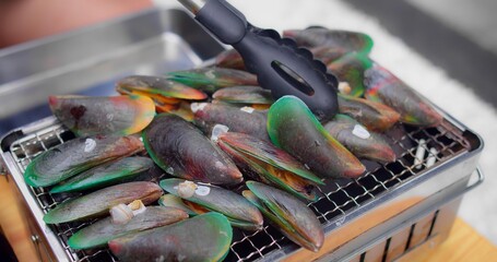 Grilled Mussels on Barbecue Grill with Tongs - Fresh Seafood Cooking Outdoors in Vibrant Green Shells