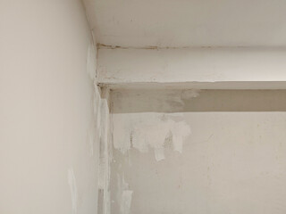 Detailed view showcasing the corner where the wall meets the ceiling, revealing patches and irregularities on the surface, perfect for illustrating renovation work and construction textures.
