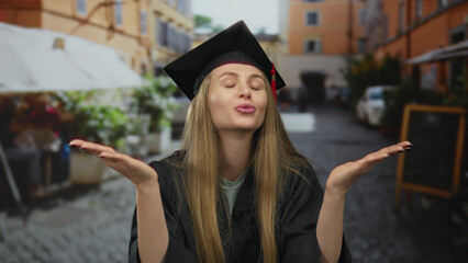 Graduated woman in a cap and gown sending a kiss in a lively city street with colorful buildings.