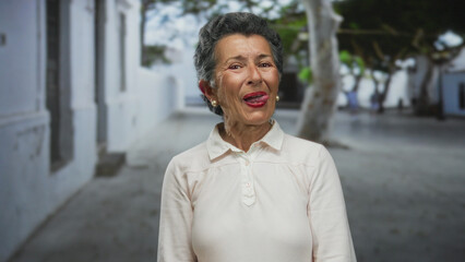 Senior woman with grey hair playfully posing on an urban street, blending warmth and charm in a...