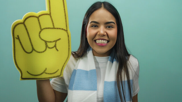 Woman enthusiastically cheering with a large foam finger in front of an isolated green background, showcasing vibrant spirit and joyful energy. - Powered by Adobe
