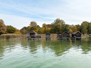 Obraz premium Wooden boathouses on stilts over calm lake water in autumn nature landscape