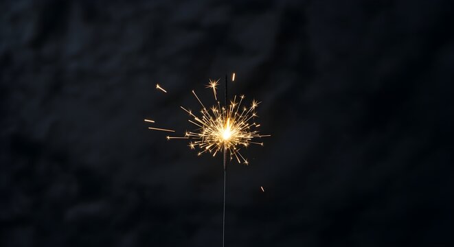 A single burning sparkler against a dark background, a festive preparation for a happy new year celebration