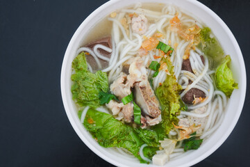 Bowl of Vietnamese noodle soup with meat and vegetables.