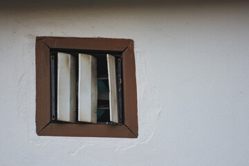 Obraz premium White drainpipe on building, with a small barred window.