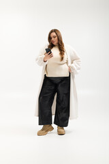 Fototapeta premium Plus size young woman in cozy knitted sweater poses in bright studio