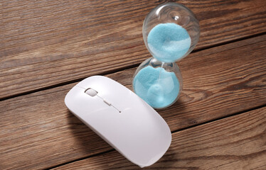 Pc mouse and hourglass on wooden table.