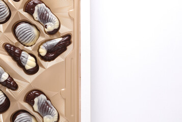 Box of chocolate candies in the shape of sea shells on a white background. Top view