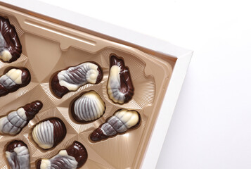 Box of chocolate candies in the shape of sea shells on a white background. Top view