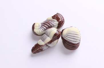 Chocolate candies in the shape of sea shells on white background.