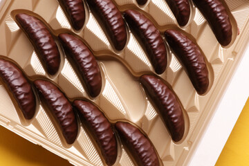 Box of chocolate candies on yellow background. Top view