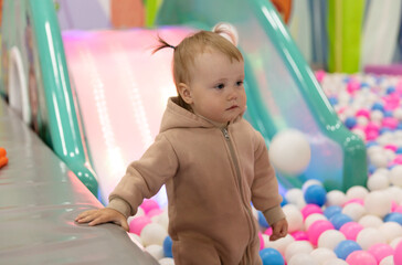 Cute little baby plays with balls in a dry pool at a children's entertainment center