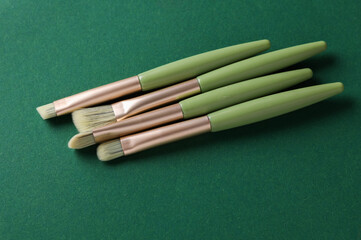 Premium makeup brushes set on green background. Beauty concept