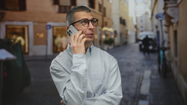 Man using smartphone on a sunny european street conveys connectivity in an urban outdoor setting, dressed in casual attire.