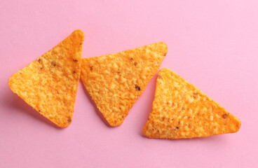Triangular appetizing corn tortilla chips slices on pink background