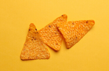 Triangular appetizing corn tortilla chips slices on yellow background