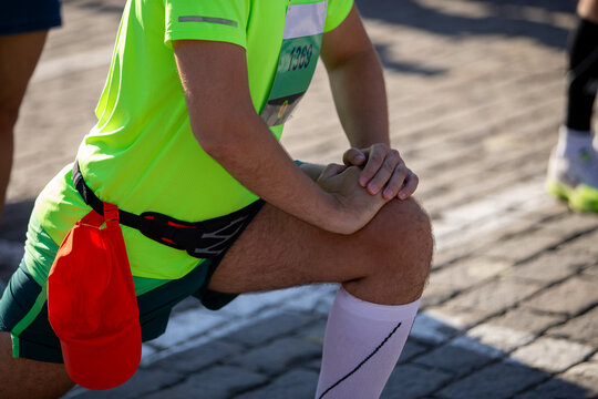 Athlete runner warming up his legs before marathon run - Powered by Adobe