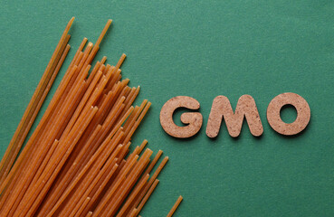 Pasta and word gmo on green background. Bioengineering. Genetically modified products
