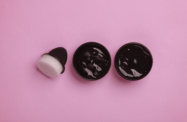 Shoe polish jar with sponge on pink background. Top view