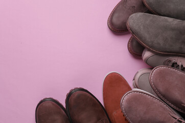 Different pairs of men's shoes on a pink background. Top view. Copy space