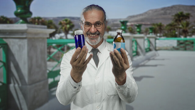 Middle aged scientist man in lab coat holding a medicine bottle with both hands on building terrace smiling; confidence wellness trust.