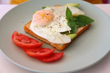 Savory breakfast plate in Albania. Avocado toast with fried egg and tomato.