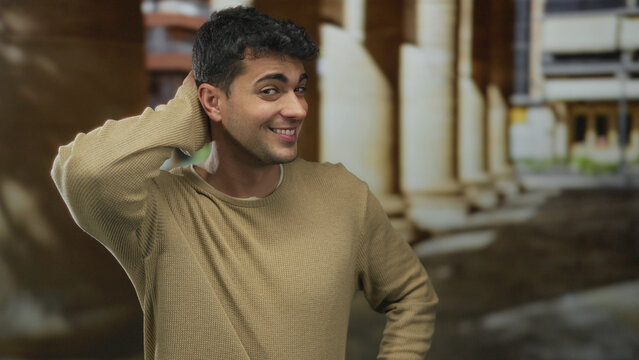 Man rubs head in scratch pose outdoor sporting hispanic young features with an unsure look as a guy displays a sheepish gesture.