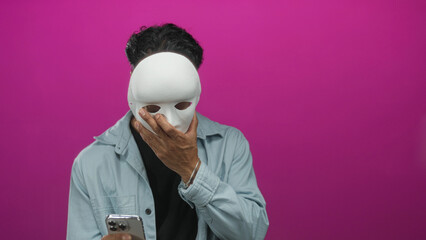 Young man reading message on smartphone screen with serious expression and focused posture in studio; concentration.
