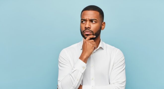 Man in white shirt pondering with hand on chin