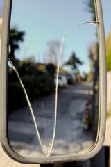 A fractured, curved safety mirror with a V-shaped crack, designed for driveway visibility. It...