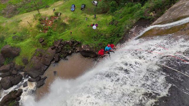 top-close drone view of three people abseiling a waterfall in Minas Gerais