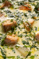 Close-up of a creamy salmon soup garnished with fresh herbs and pieces of salmon creating a rich and appetizing presentation