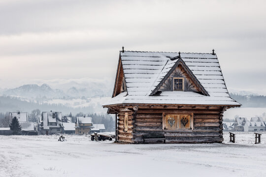 Wooden cabin in snowy landscape with mountains behind