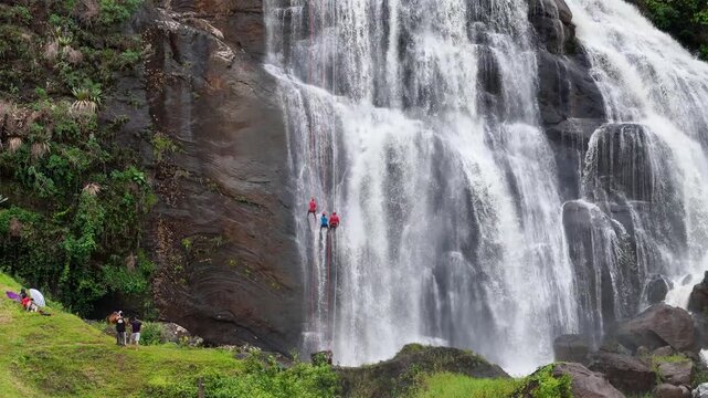 Cinematic 70mm Drone Shot of Three People Abseiling Down a Massive Waterfall in Faria Lemos, Minas Gerais, Brazil