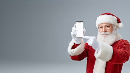 Santa Claus in festive red suit and hat, holding smartphone with blank screen, pointing at it, showcasing holiday spirit and modern technology with copy space