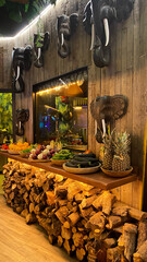 Vibrant display of fresh fruits and vegetables on wooden table in a rustic restaurant interior with elephant decor and warm lighting ambiance