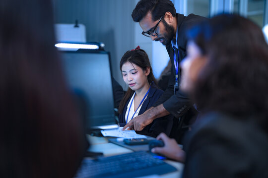 A diverse team of AI strategists, led by a focused man with glasses, develops a new service platform. Two female colleagues analyze data and document the implementation plan in a modern tech hub.