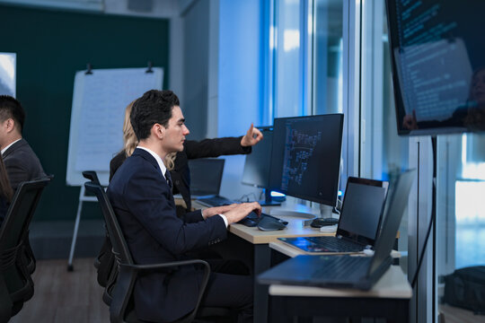 A diverse and dedicated team of professionals works diligently in a bustling, modern tech office at night, collaborating and focusing on their tasks to meet a critical project deadline.